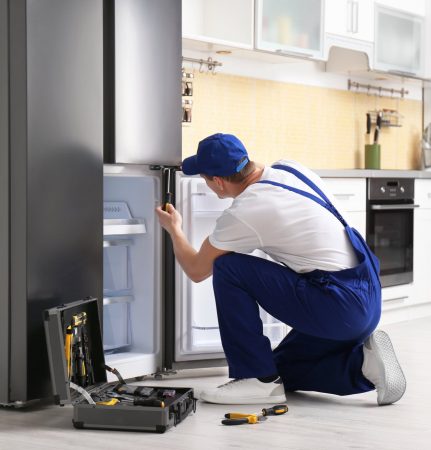 a technician repairing a refrigerator - Brooklyn Appliance Repair Pros